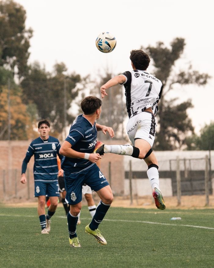 Exciting moment in a soccer match as players leap for the ball on a field.